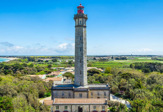 A tall lighthouse surrounded by lush fields and coastline in the vicinity of Rivedoux-Plage, Île de Ré, France.