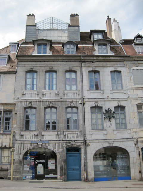 Fachada de edificio histórico con puerta y ventanas azules en Bourgogne-Franche-Comté, Francia.