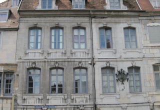 Gevel van een historisch gebouw met blauwe deur en ramen in Bourgogne-Franche-Comté, Frankrijk.