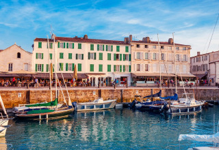 Scenic harbor with sailboats and lively buildings at Flower Camping Le Platin - La Redoute, Île de France.