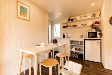 Vue intérieure d'une tente safari confortable avec table, tabourets et kitchenette au Flower Camping Le Platin.