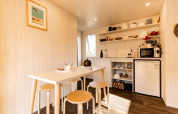 Interior view of a cozy safari tent with dining table, stools, and kitchenette at Flower Camping Le Platin.