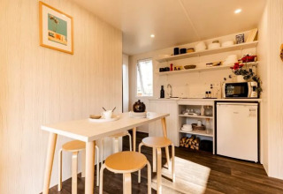 Vue intérieure d'une tente safari confortable avec table, tabourets et kitchenette au Flower Camping Le Platin.