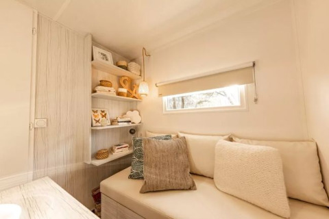 Intérieur chaleureux du lodge Coco Sweet Comfort avec canapé et étagères chez Flower Camping Le Platin, France.