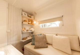 Intérieur chaleureux du lodge Coco Sweet Comfort avec canapé et étagères chez Flower Camping Le Platin, France.