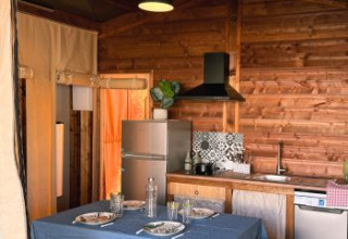 Cuisine et table à manger dans une tente safari Cottons Flower Comfort au Flower Camping Le Platin - La Redoute, France.