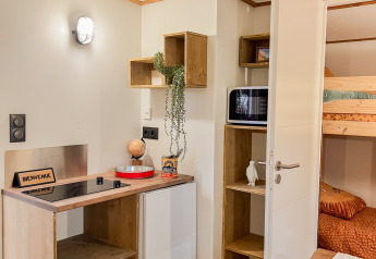 Acogedora cocina y comedor en una cabaña del Flower Camping Le Platin - La Redoute en Francia, con literas.