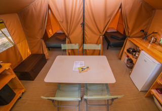 Innenansicht des Safari-Ponza-Zeltes bei Onlycamp Camping Les Vailhès mit Tisch, Betten und Küchenzeile.