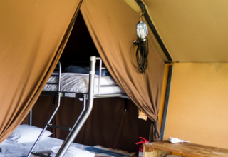 Binnenzicht van de Ponza safaritent met stapelbedden bij Onlycamp Camping Les Tuillères in Frankrijk.