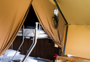 Vue intérieure de la tente safari Ponza avec lits superposés à Onlycamp Camping Les Tuillères en France.
