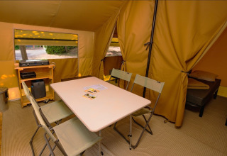 Indvendigt billede af et Ponza safari telt med bord, stole, sengerum og udstyr til camping.