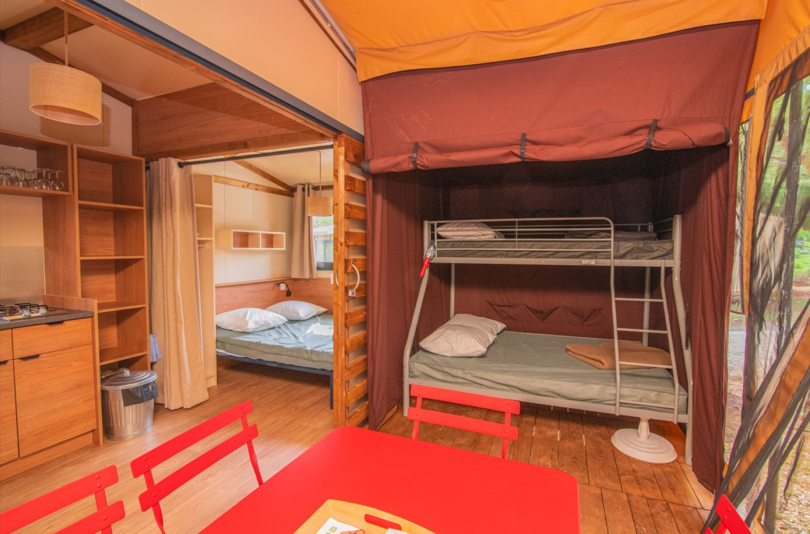 Binnenaanzicht van de safari-tent Tiny House Galli met stapelbed, tweepersoonsbed en keuken bij Onlycamp Camping Les Vailhès in Frankrijk.