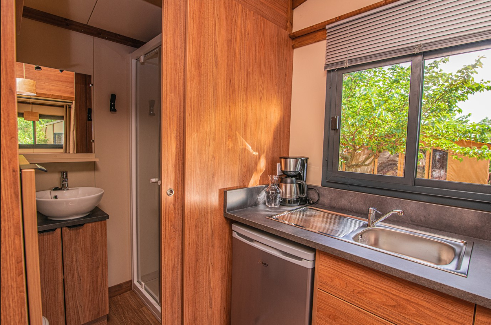 Binnenaanzicht van een kleine keuken en badkamer in de Tiny House Galli safaritent op Onlycamp Les Vailhès, Frankrijk.