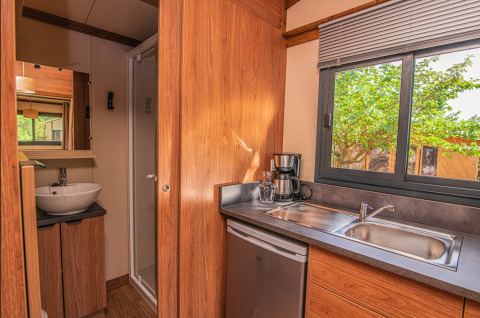 Indvendigt billede af et lille køkken og badeværelse i Tiny House Galli safari-telt på Onlycamp Les Vailhès.