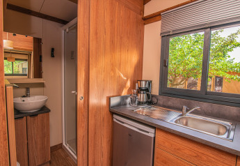 Vista interior de una pequeña cocina y baño en la tienda safari Tiny House Galli de Onlycamp Les Vailhès, Francia.
