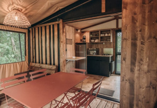 Interieur van safari tent Galli Tiny-house op Onlycamp Camping Les Tuillères in Frankrijk met keuken en eetruimte.