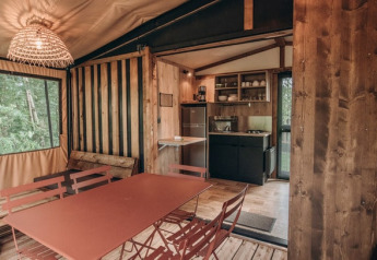 Interno della tenda safari Galli Tiny-house a Onlycamp Camping Les Tuillères, Francia, con cucina e zona pranzo.