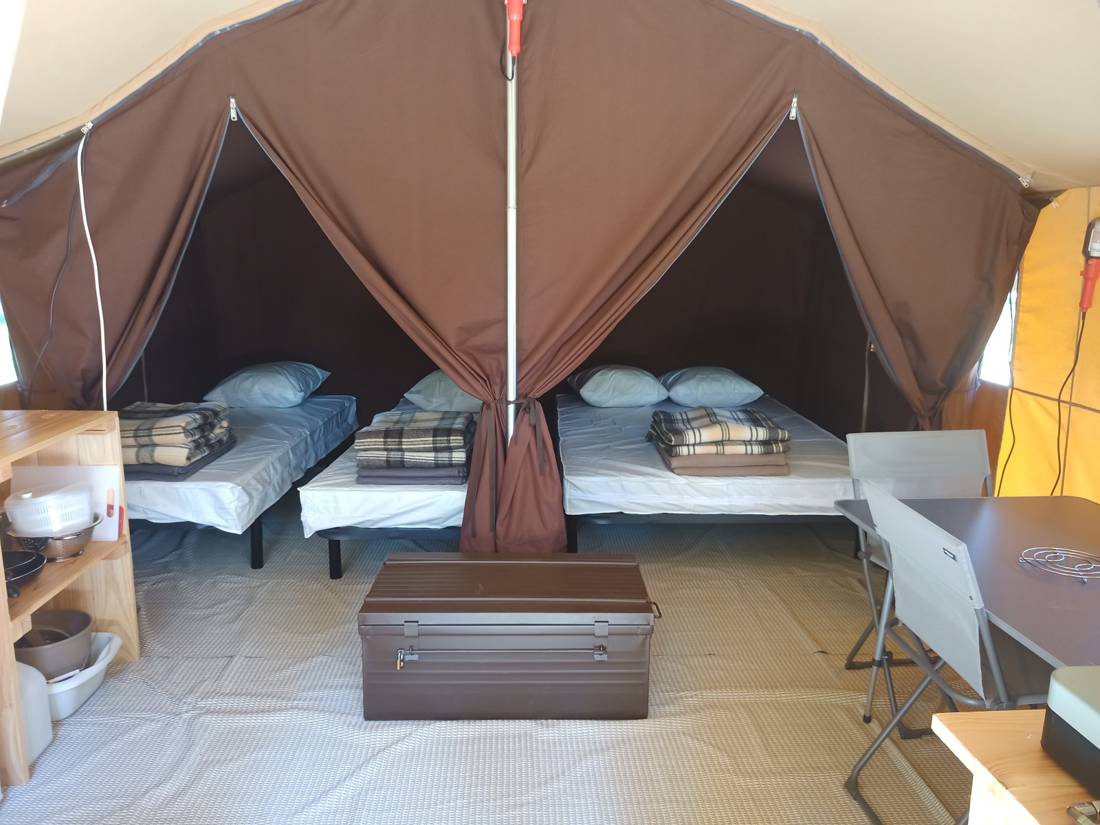 Binnenaanzicht van de Ponza safaritent bij Onlycamp Camping le Champ d'Eté in Frankrijk met drie bedden.