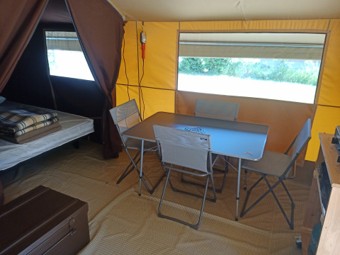 Interno della tenda safari Ponza a Onlycamp Camping le Champ d’Eté in Francia, con tavolo e sedie.