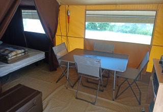 Interno della tenda safari Ponza a Onlycamp Camping le Champ d’Eté in Francia, con tavolo e sedie.