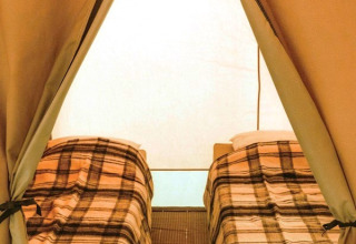 Interno di una tenda safari Ponza con due letti singoli e coperte a quadri, illuminazione naturale.