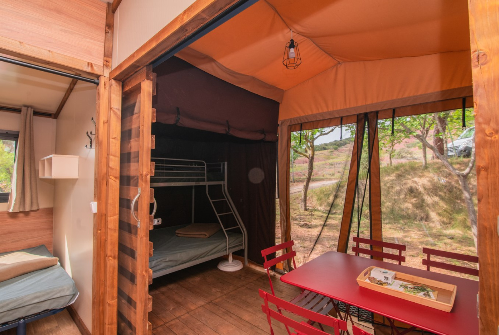 Binnenkant van safaritent Tiny-house Galli op Onlycamp Camping Chamarges in Frankrijk, met stapelbed en tafel.