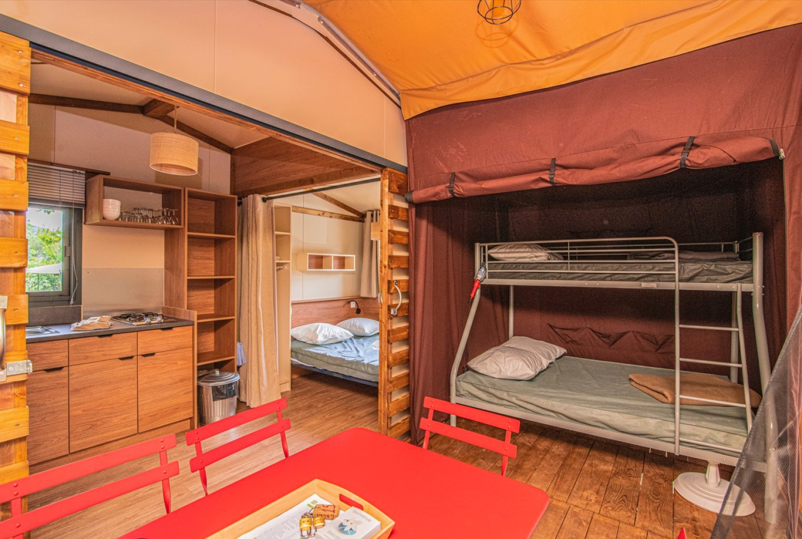 Interieur van safaritent Tiny-house Galli met keuken, stapelbed en tafel bij Onlycamp Camping Chamarges, Frankrijk.
