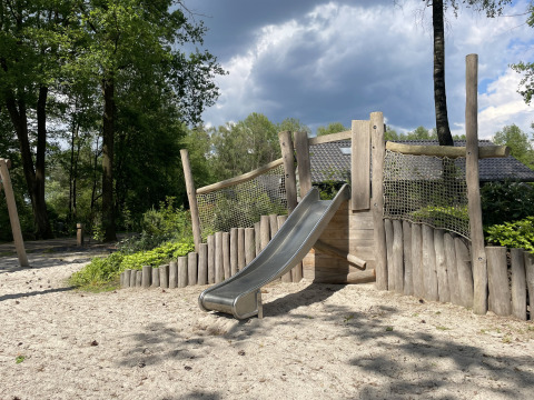 Parque infantil con tobogán en Holiday park Latour, rodeado de árboles en Noord-Brabant, Países Bajos.