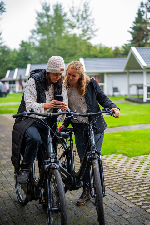 Two women with bikes looking at a phone at Holiday park Latour in North-Brabant, Netherlands.