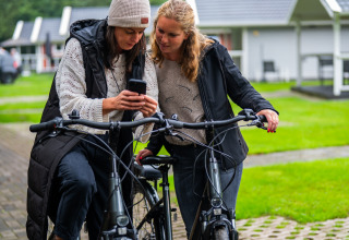 Two women with bikes looking at a phone at Holiday park Latour in North-Brabant, Netherlands.
