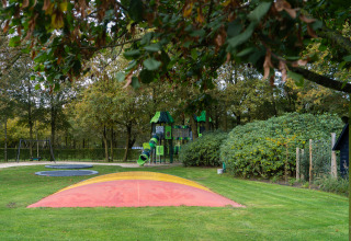 Playground at Holiday park Latour in North-Brabant, Netherlands, with slides, swings, and lush green scenery.