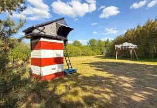 Glampingaccommodatie met verhoogde daktenten en kleurrijke hutten bij Dachzelt Dorf Sandstedt in de natuur.