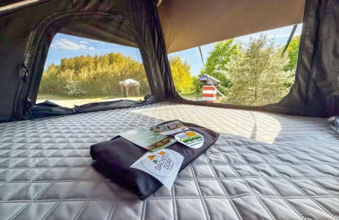 Inside a glamping tent at Dachzelt Dorf Sandstedt, Lower Saxony, with a cozy bed and nature views.