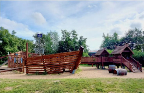 Spielplatz mit Piratenschiff bei Dachzelt Dorf Sandstedt Glamping in Niedersachsen, umgeben von Bäumen.