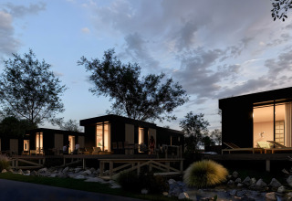 Evening scene of modern lodges with glowing windows at Valkhof met Hottub in Veluwe park de Bosgraaf, Netherlands.