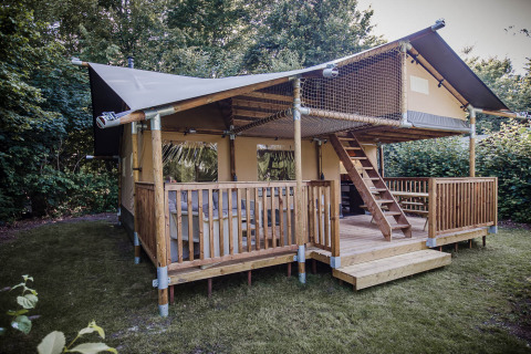 Safaritent met de naam Ranger Lodge met houten veranda, slaapzolder en omgeven door veel groen.
