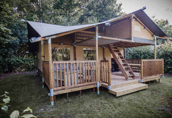 Safaritent met de naam Ranger Lodge met houten veranda, slaapzolder en omgeven door veel groen.