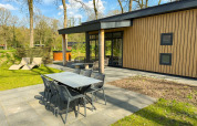 Outdoor patio with dining table, lounge chairs, and hot tub at Wood Cottage, Campsite de Witte Berg, Netherlands.