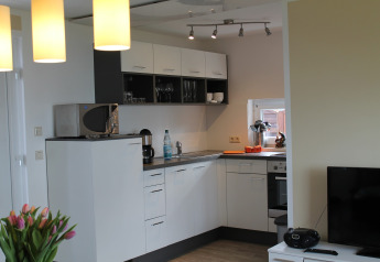 Modern kitchen at the lodge named 'Am Strand' in Germany, featuring white cabinets and natural light.