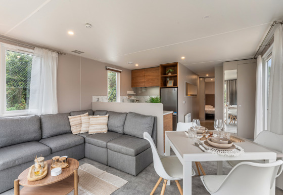 Zona giorno luminosa nel chalet Vakantiehuis Deluxe con divano grigio, tavolo da pranzo e cucina moderna.