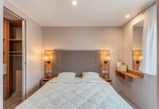 Camera moderna nel chalet Vakantiehuis Deluxe al Camping Papillon, Belgio, con letto matrimoniale e armadio.