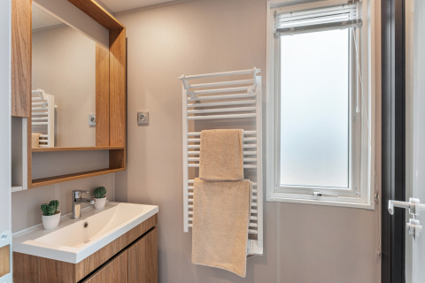 Bagno moderno allo chalet Vakantiehuis Deluxe con mobile in legno, lavandino, specchio e porta asciugamani.