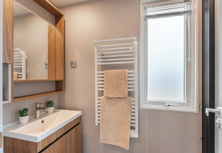 Bagno moderno allo chalet Vakantiehuis Deluxe con mobile in legno, lavandino, specchio e porta asciugamani.