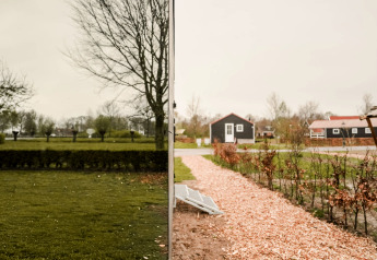 Spiegelhaus im Holiday Park Eigen Wijze, Niederlande, mit Blick auf Garten und kleine Häuser.