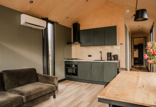 Intérieur moderne d'une tiny house au Holiday park Eigen Wijze aux Pays-Bas, avec cuisine et salon.