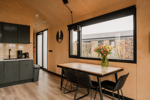 Cuisine moderne et coin repas d’un tiny house au Holiday park Eigen Wijze, Pays-Bas, avec fleurs sur la table.