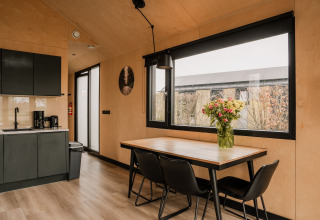 Cocina y comedor modernos en tiny house del Holiday park Eigen Wijze, Holanda, con flores en la mesa.