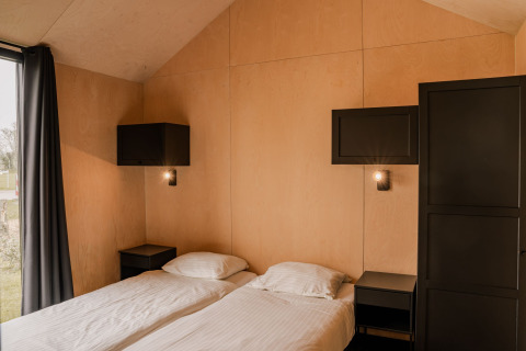 Soveværelse i et lille hus på Holiday park Eigen Wijze i Holland med to enkeltsenge og moderne indretning.