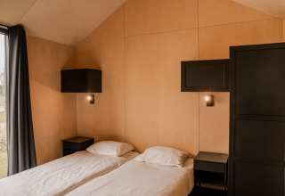 Chambre dans une tiny house au Holiday park Eigen Wijze, Pays-Bas, avec deux lits simples et déco épurée.