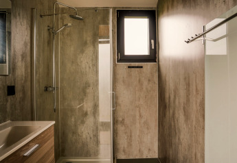 Salle de bain moderne avec douche, lavabo et petite fenêtre dans un tiny house au Holiday park Eigen Wijze, Pays-Bas.